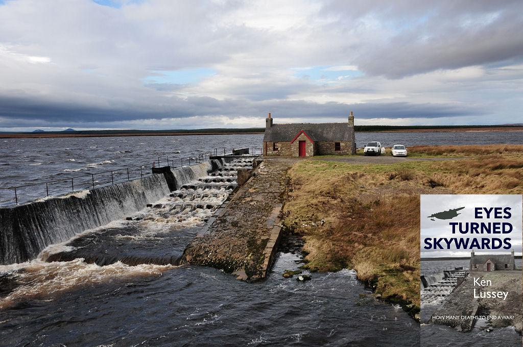 This modern image shows a broad expanse of choppy grey water across the bottom half of the frame with a thin line of land beyond it then grey skies. Intruding into the bottom right of the frame is a grassy promontory which has a stone cottage with red trimmings placed on it. There are two vehicles next to the cottage. To the left of the cottage and extending down to the bottom left of the frame is a fish ladder comprising a wall with water cascading over it, and steps to its right. The front cover of ‘Eyes Turned Skywards’ is shown in the bottom right corner.