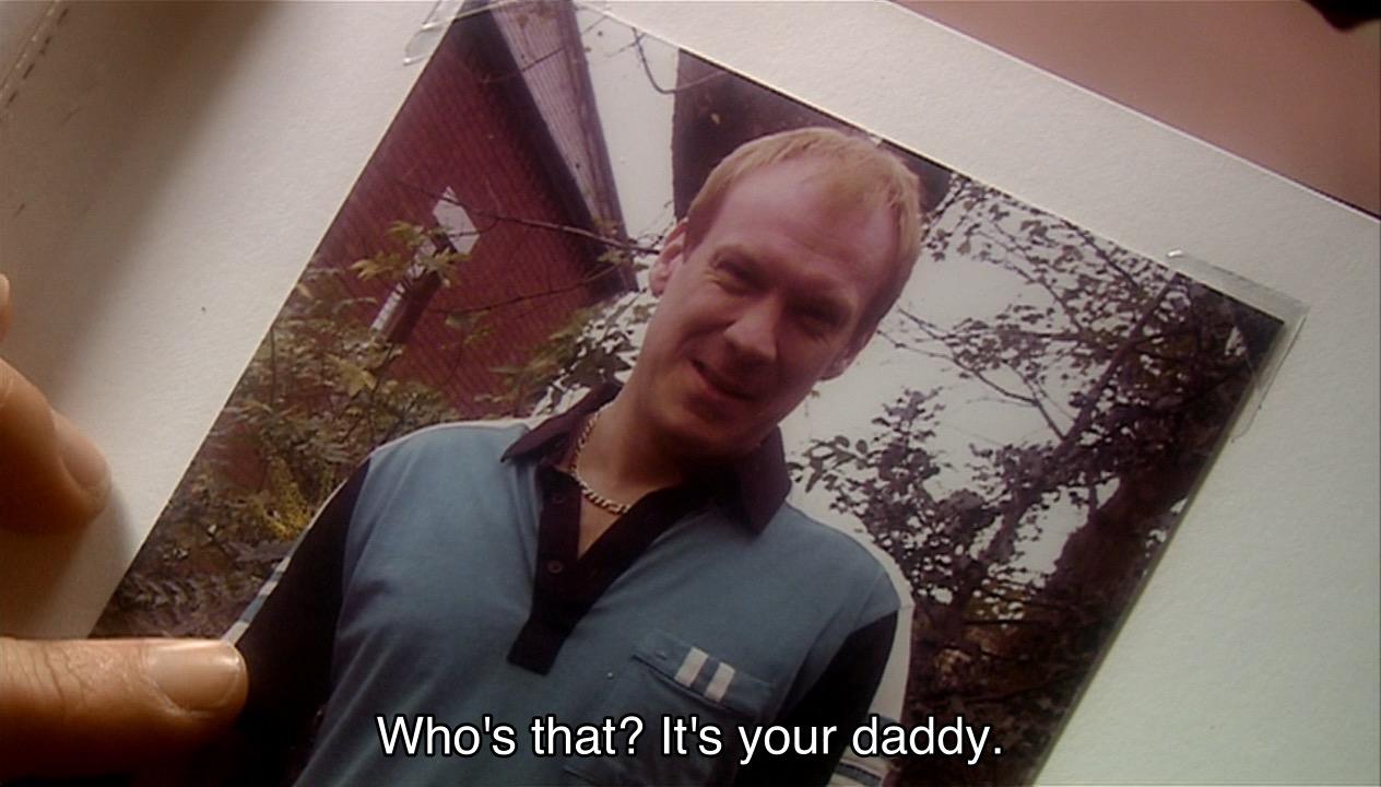 Christopher Eccleston episode. Closeup of a picture book. (Remember those?) A hand is pointing at a picture of Pete Tyler, an extremely 1980s British guy wearing a blue polo shirt with black and white stripes and a thick gold chain necklace. Caption says, “Who’s that? It’s your daddy.” You can say that again.