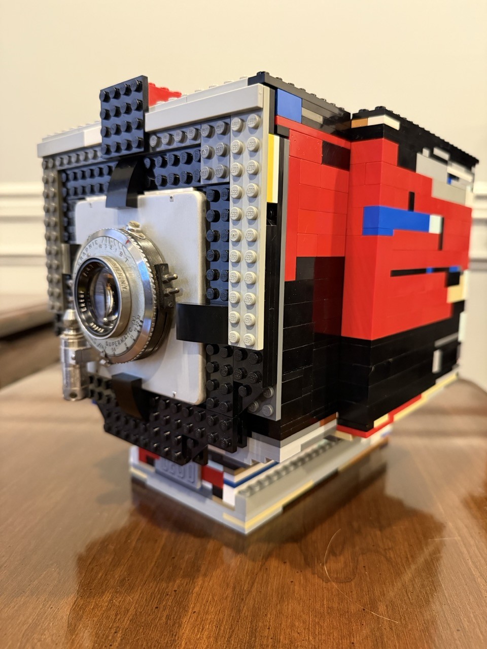 A 4x5 film camera made of lego with the lens board and lens from a Graflex Speed Graphic mounted to the front.