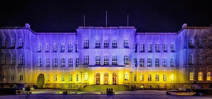 Hauptgebäude der RWTH Aachen bei Nacht, beleuchtet in bunten Farben