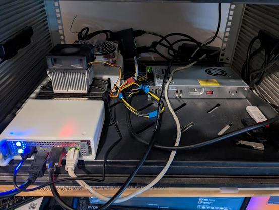 Photo of an encased B250, with an additional heatsink and fan on top of the original heatsink.
Everything is houses on a rack shelf.