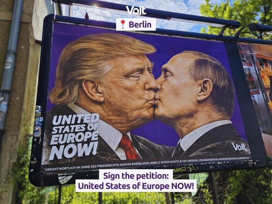 A photograph of a large billboard in Berlin featuring a painted mural of Donald Trump and Vladimir Putin kissing on the lips, both depicted in dark suits. Bold white text on the left reads "UNITED STATES OF EUROPE NOW!" against a purple background. The Volt logo appears in white in the bottom right corner of the mural. Below the image, small text credits.