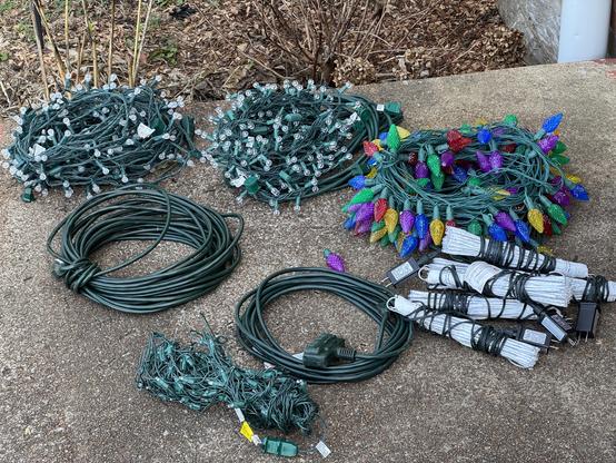 Piles of Christmas lights and electrical extension cords on a porch