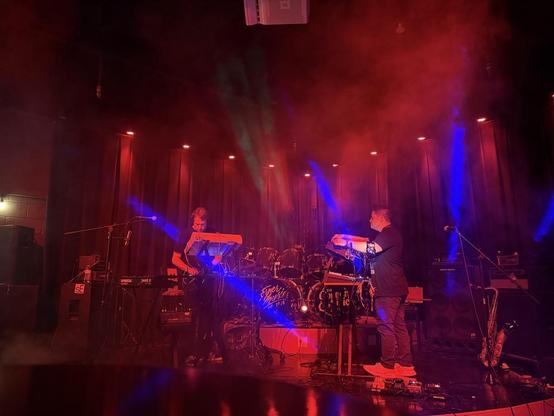 2 musicians, performing amidst red and blue lights.