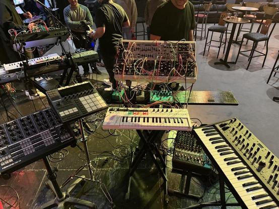 A photo of some electronic instruments, some eurorack, some keyboards and a drum machine, as configured for a live performance. 