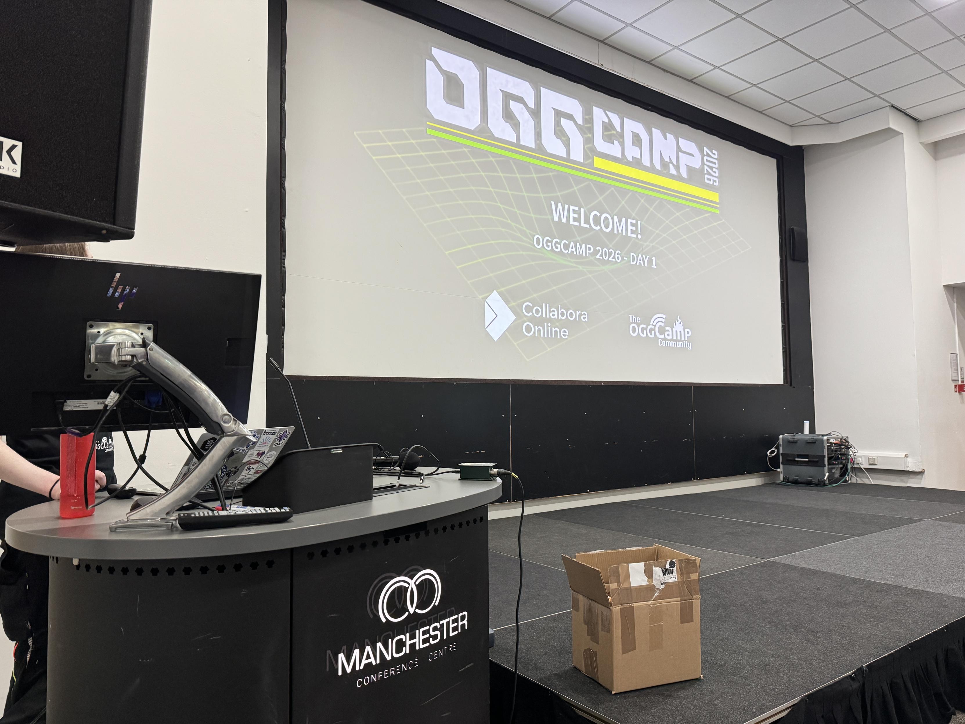 A slide showing the OggCamp 2026 logo behind a stage.
