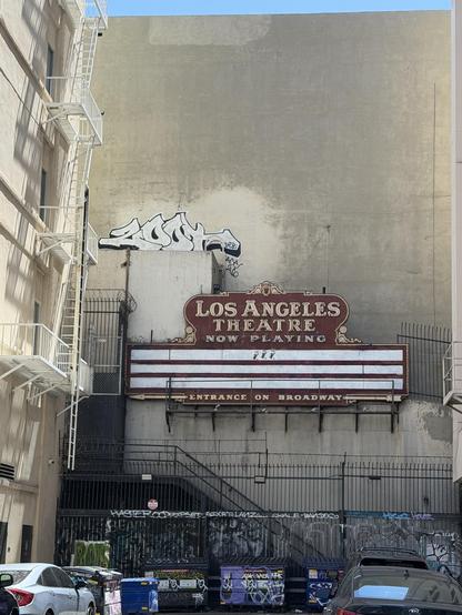 Across the old alley with a old-fashioned billboard that reads Los Angeles Theatre now playing 
