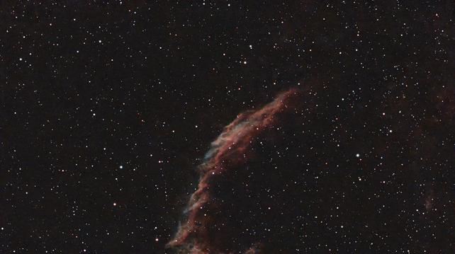 A star field With a red and green wispy filament looking cloud sticking a finger up in the middle