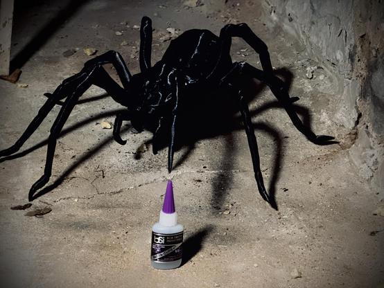 A large 3d printed spider touching a bottle of CA glue, for scale.  