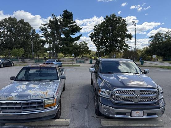 Two Dodge trucks, an 80's Dakota parked next to a modern RAM 1500. 